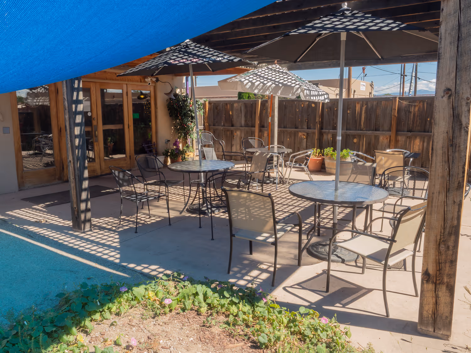 Shaded patio with round tables, chairs and umbrellas under a wooden pergola